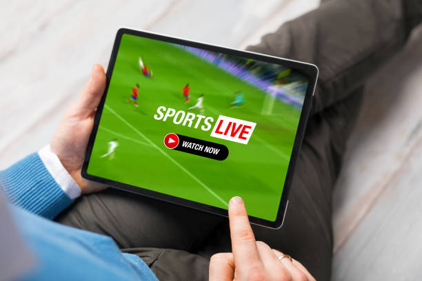 Man relaxing at home and watching live stream of football match on tablet